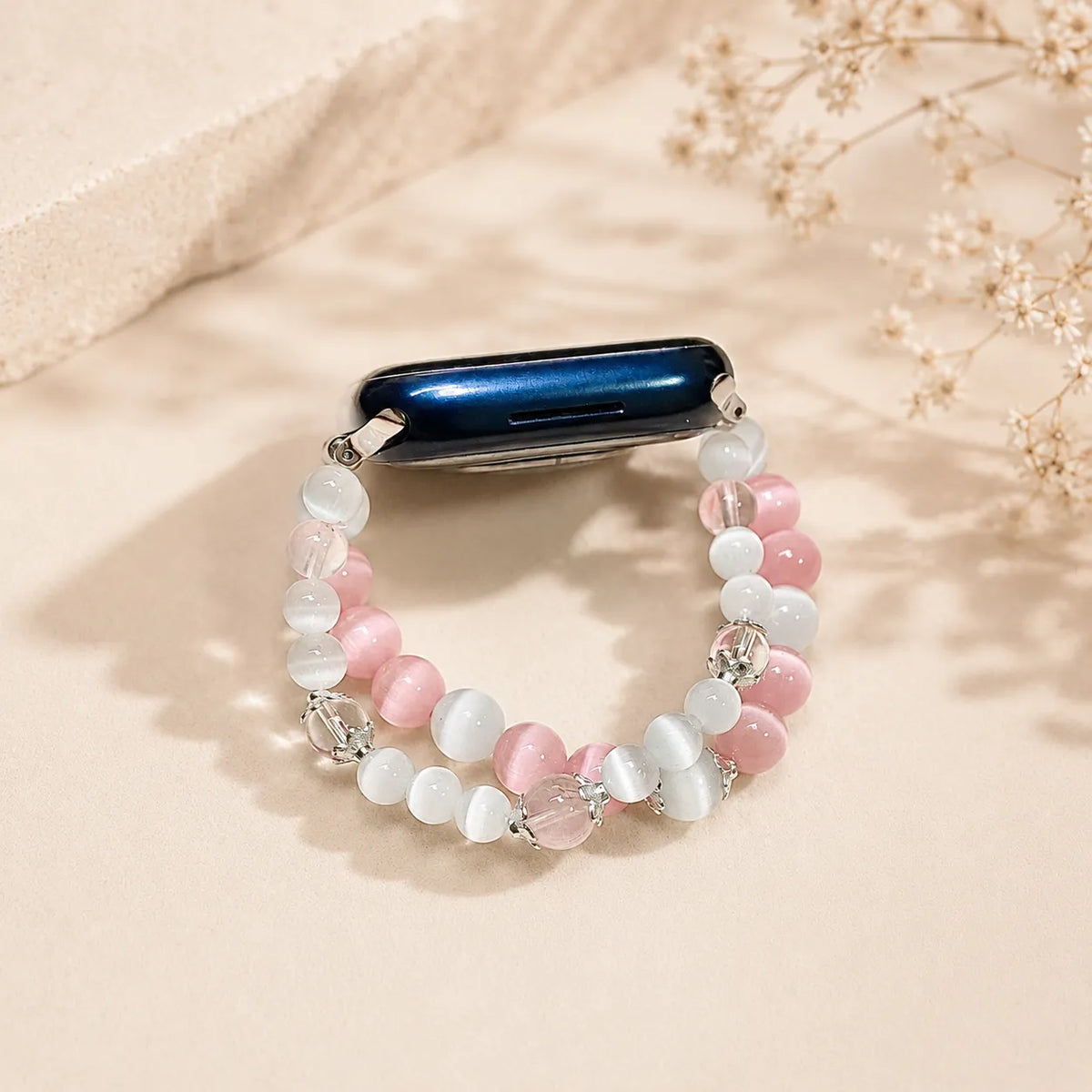 Cinturino First Love rosa e bianco per Apple Watch disposto come un bracciale sovrapposto