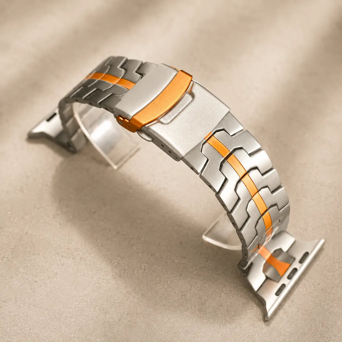 Folding clasp and layered links on an orange and silver Apple Watch band