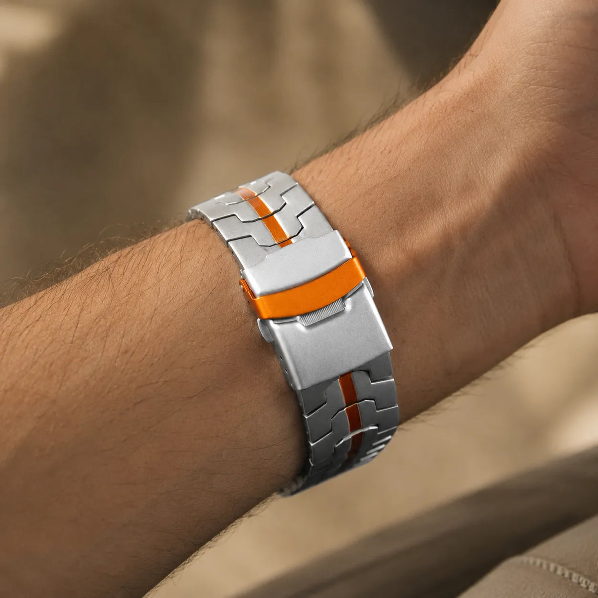 Iron Man inspired stainless steel Apple Watch band with orange stripe worn on the wrist