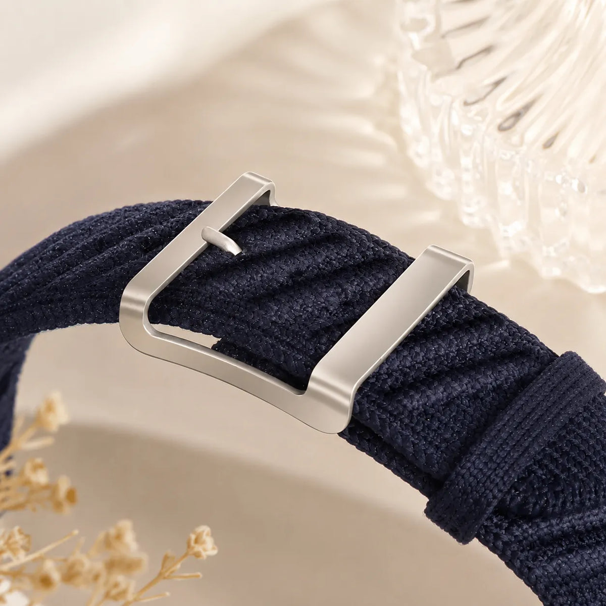 Metal pin buckle fitted through the open knit structure of a blue nylon Apple Watch band