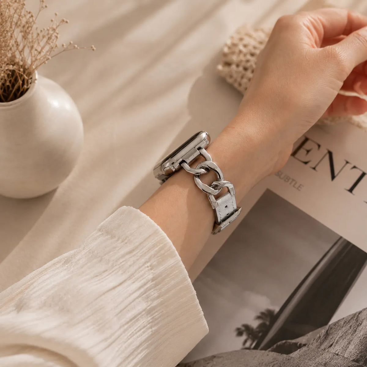 Silver leather Apple Watch band with oversized polished chain links worn on the wrist