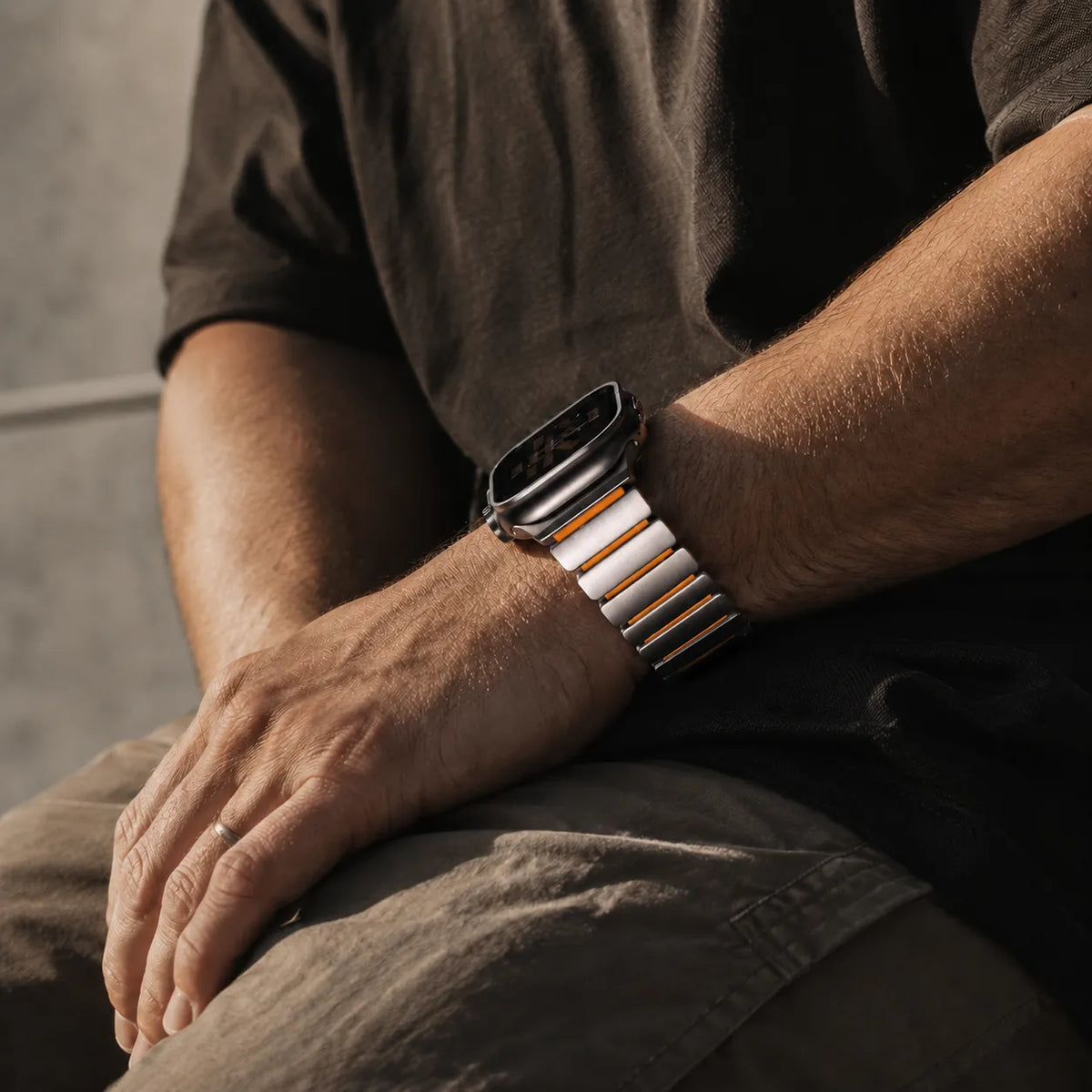 Silver and orange metal silicone Apple Watch link band worn on the wrist