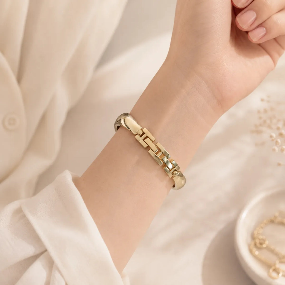 Goldfarbenes minimalistisches Edelstahlarmband für die Apple Watch zu einem hellen neutralen Ärmel