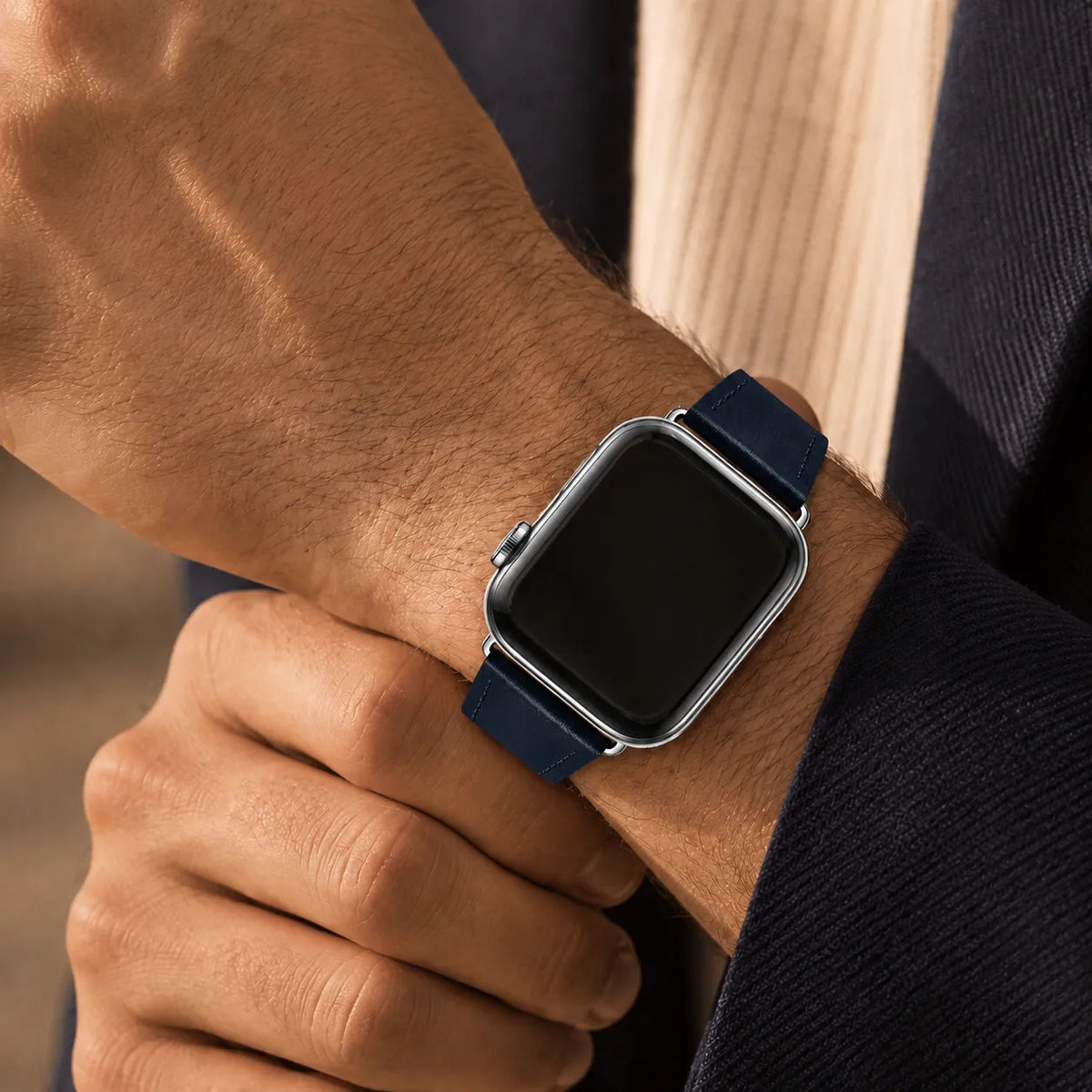 Bracelet Apple Watch en cuir bleu marine porté avec une tenue sombre en maille