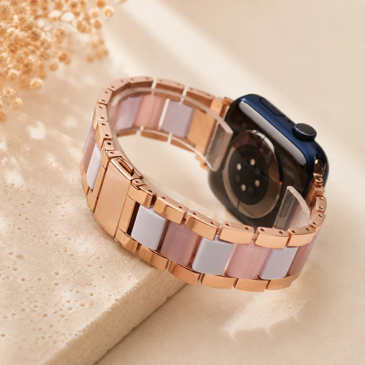 손목에 착용한 로즈 골드 레진 & 메탈 Apple Watch 밴드
